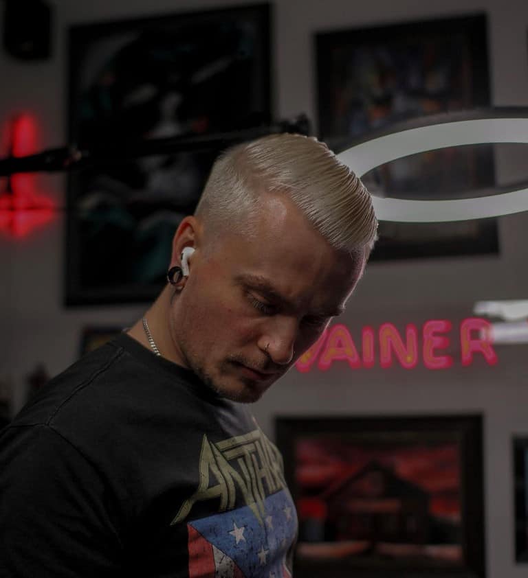 blonde tattoo artist looking down with airpods in
