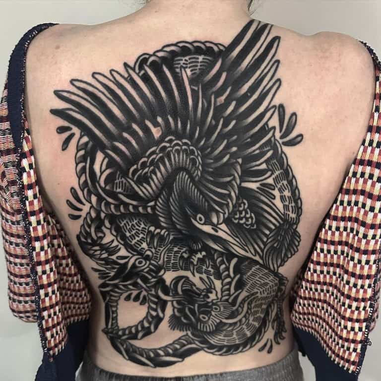 A huge back tattoo in the old-school style of an animal fighting scene