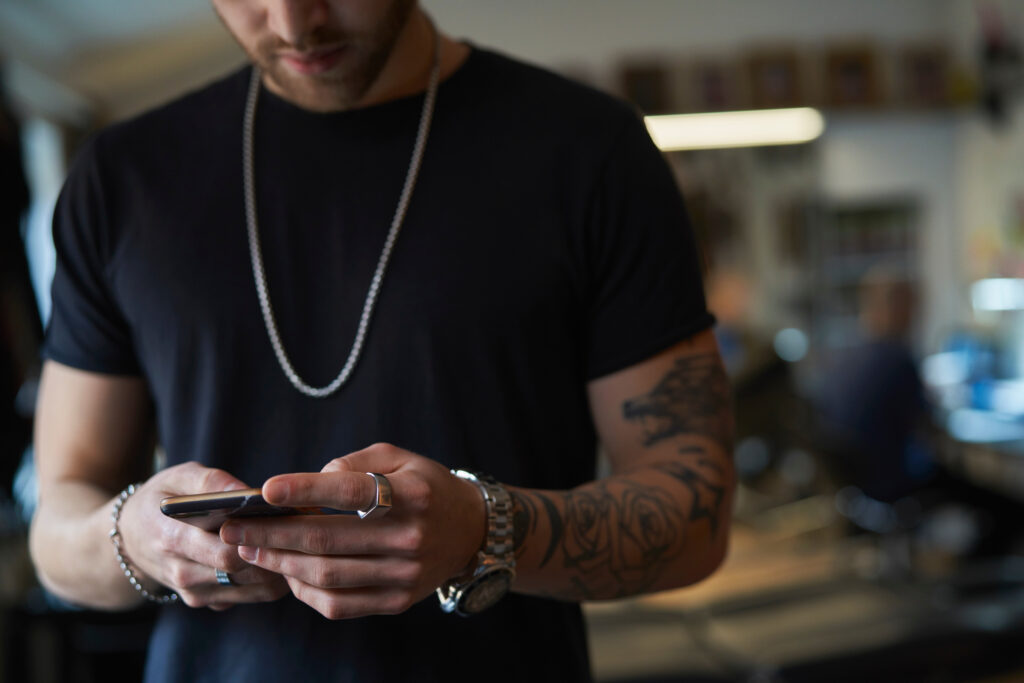 A tattoo artist using a mobile phone implying that tattoogenda is mobile compatible.